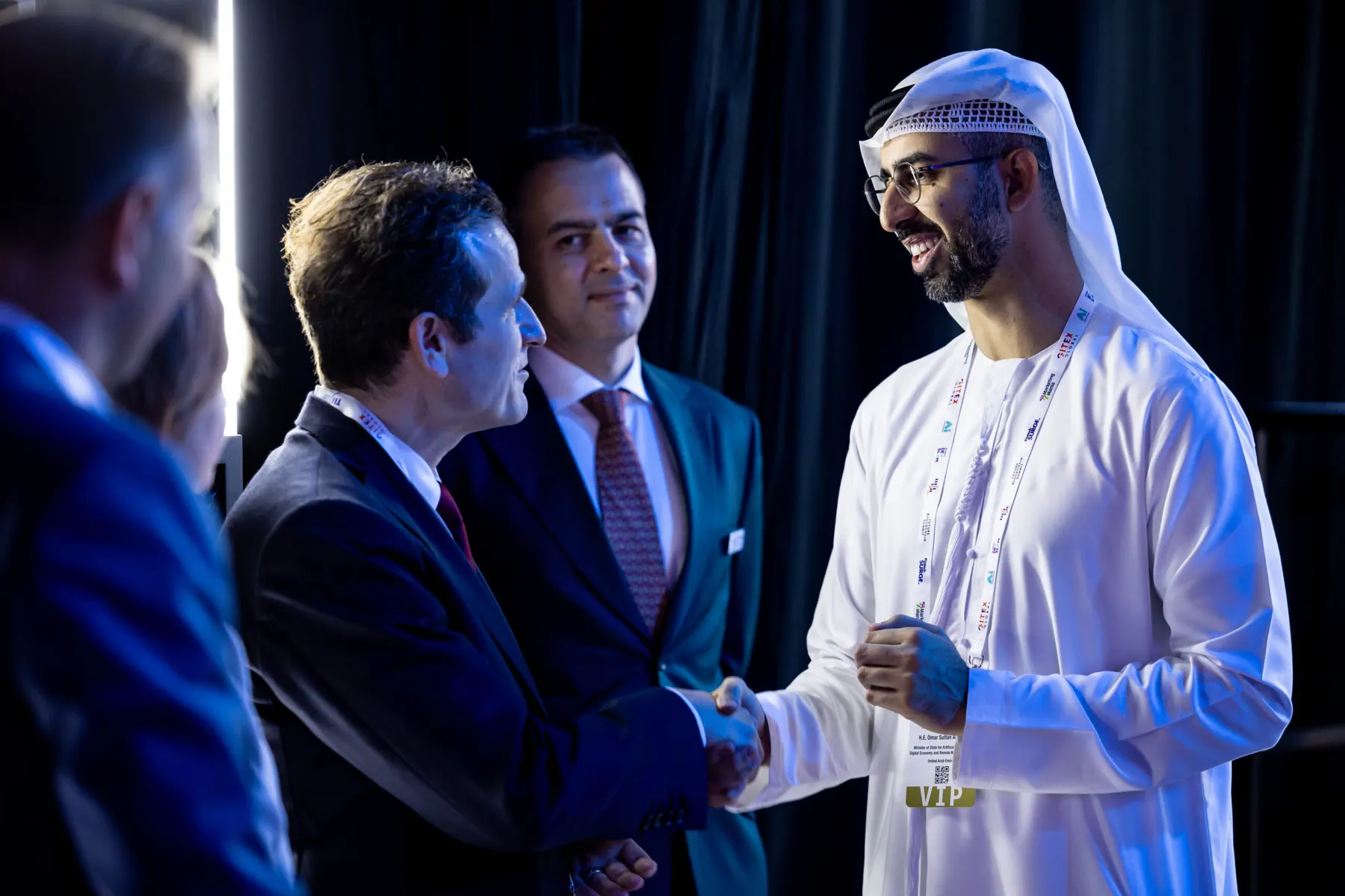 A delegate shaking hands with an Emirati official at a networking reception